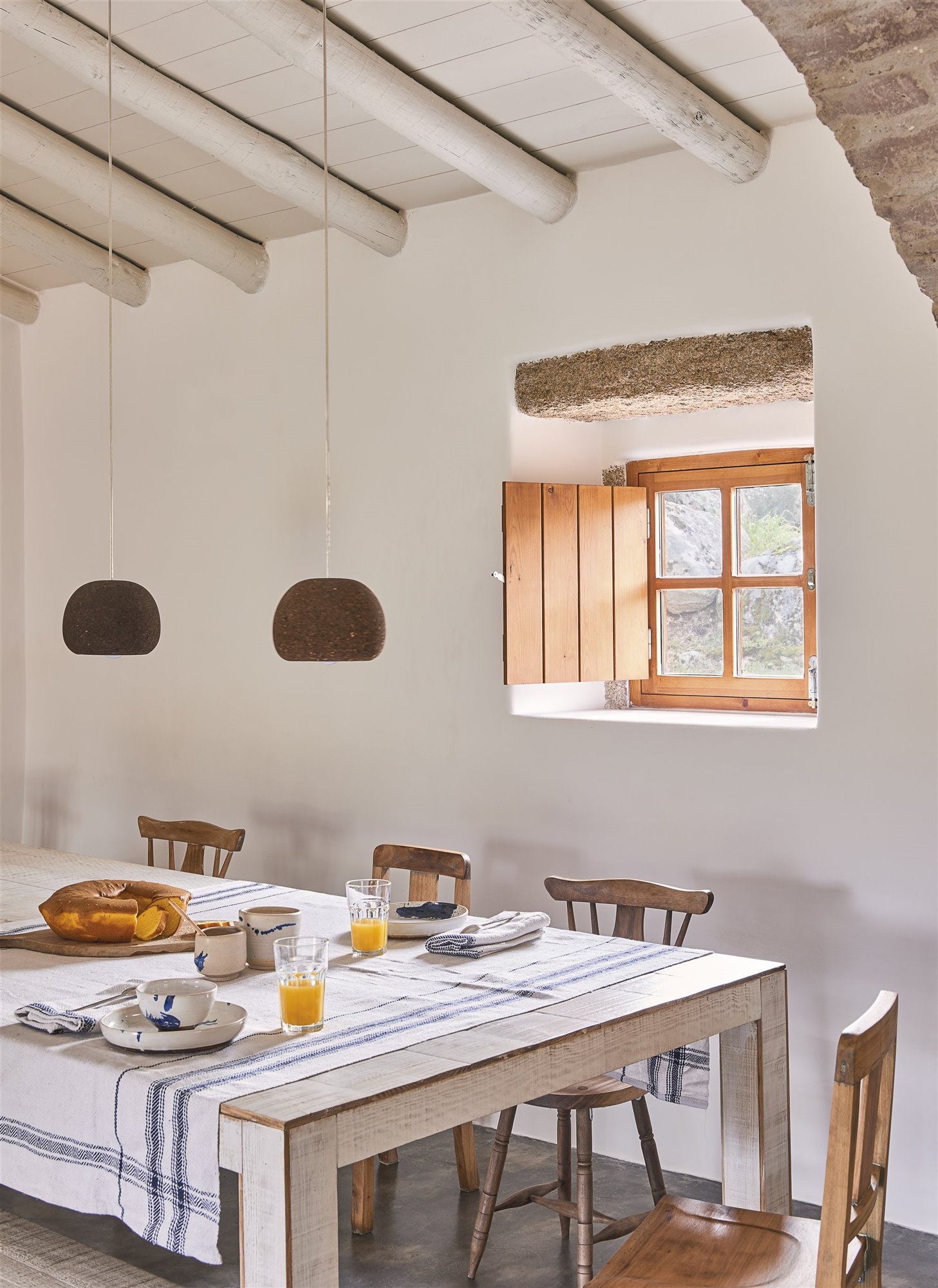 MEsa de estilo rustico con mantel de color blanco. De fondo