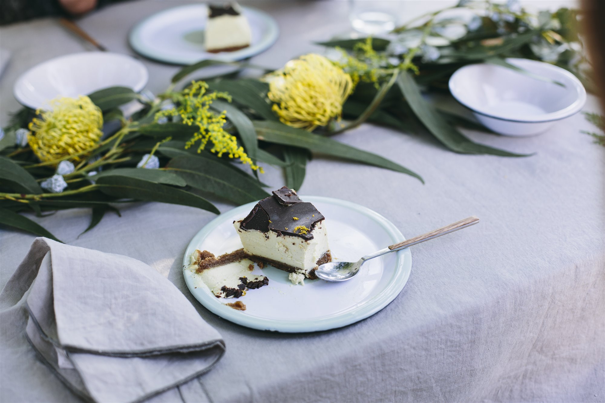 Mesa con manteles y servilletas de lino y flores naturales amarillas. La mesa