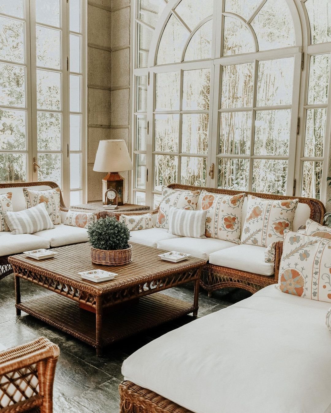 Salon con muebles de ratan y cojines con estampado de flores de la casa de Isabel Preysler
