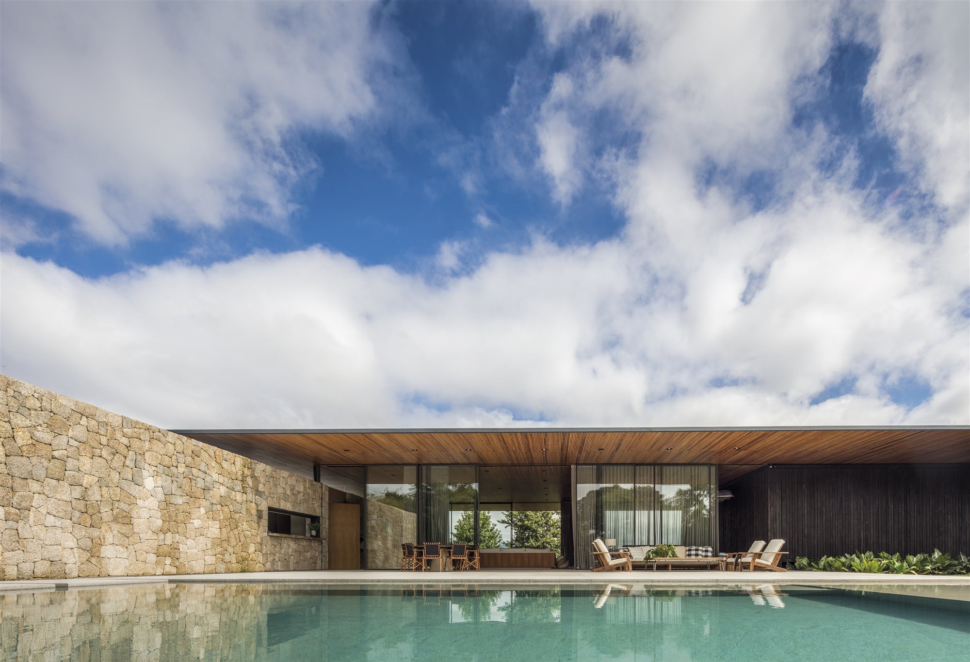 Casa de madera en Brasil rodeada de bosques piscina con muro de piedra