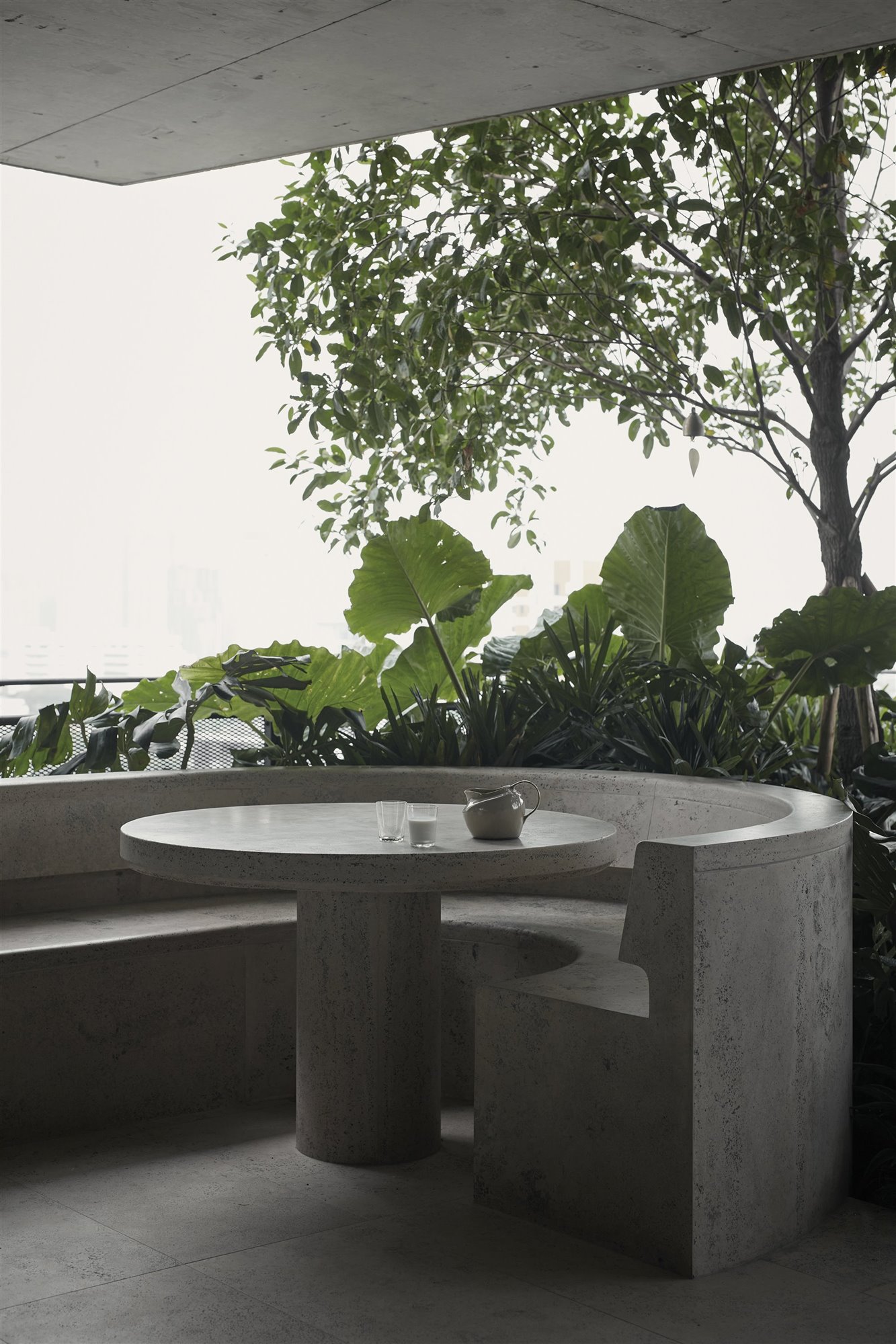 Exterior de una casa moderna con banco y mesa redonda de piedra