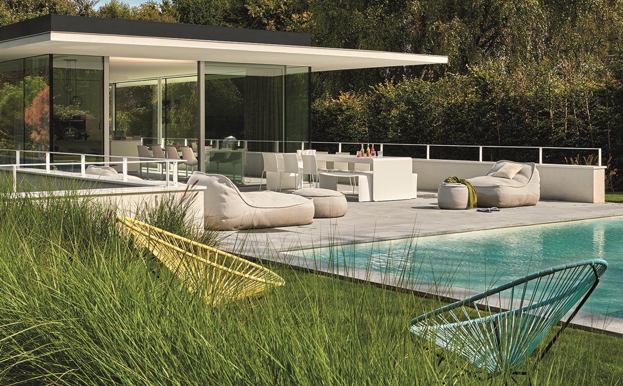 Casa de Bruno Erpicum con dos butacas Acapulco en primer plano y los sofás Float, de Francesco Rota para Paola Lenti, junto a la piscina.
