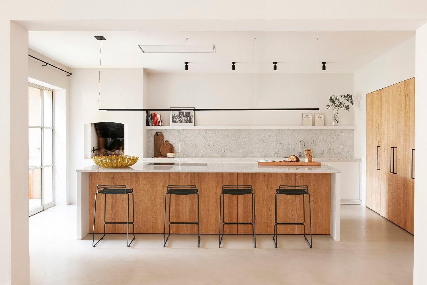 Cocina de madera y mármol con taburetes negros