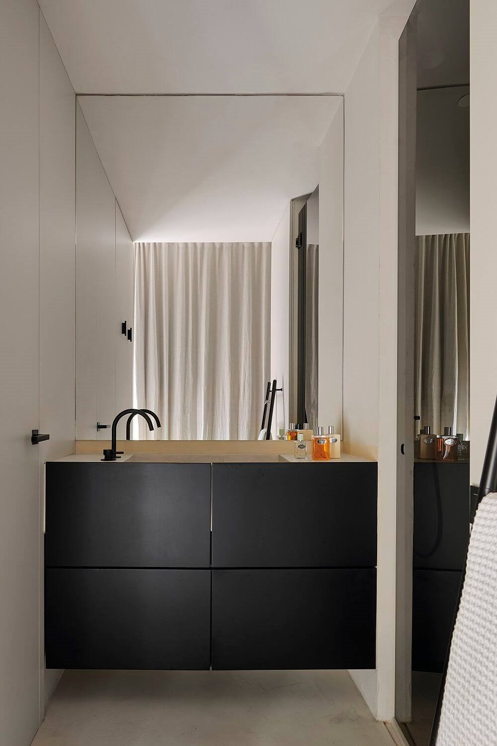Mueble de baño suspendido negro y espejo grande.