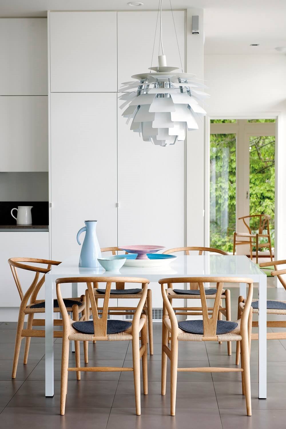 Cocina blanca con mesa blanca y sillas de madera