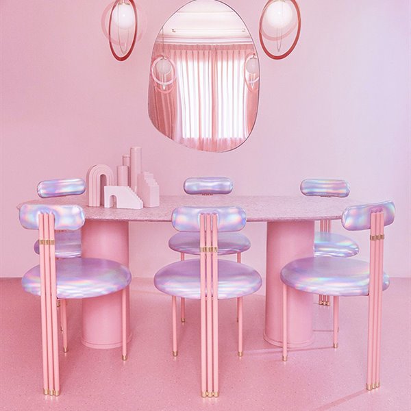 Surrealista comedor en tonos rosa con los asientos de un violeta perlado. 