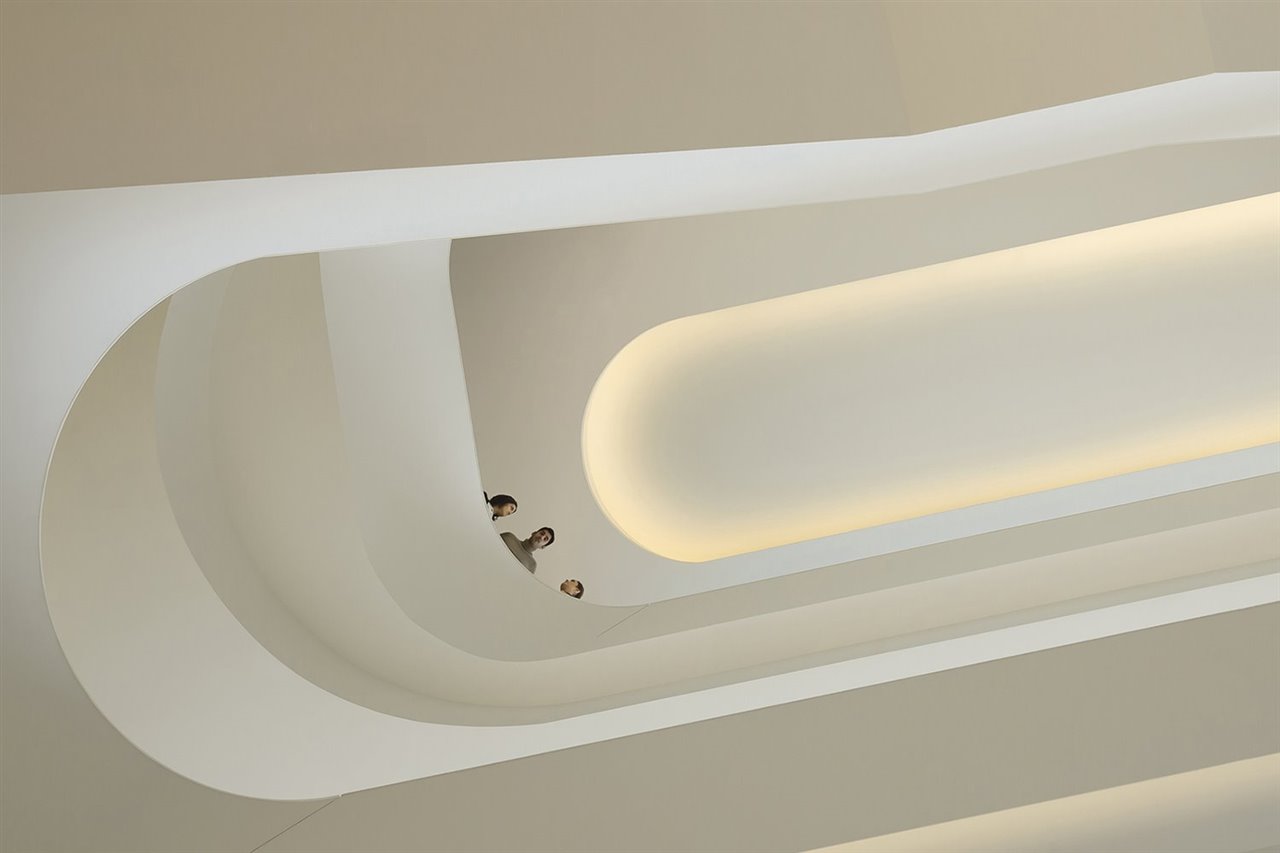 Una escultural escalera sinuosa comunica los diversos niveles en el espacio perimetral del edificio.
