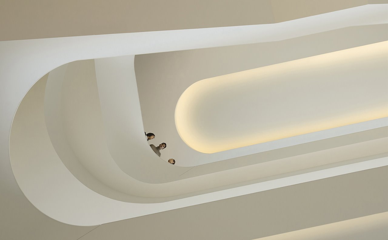 Una escultural escalera sinuosa comunica los diversos niveles en el espacio perimetral del edificio.
