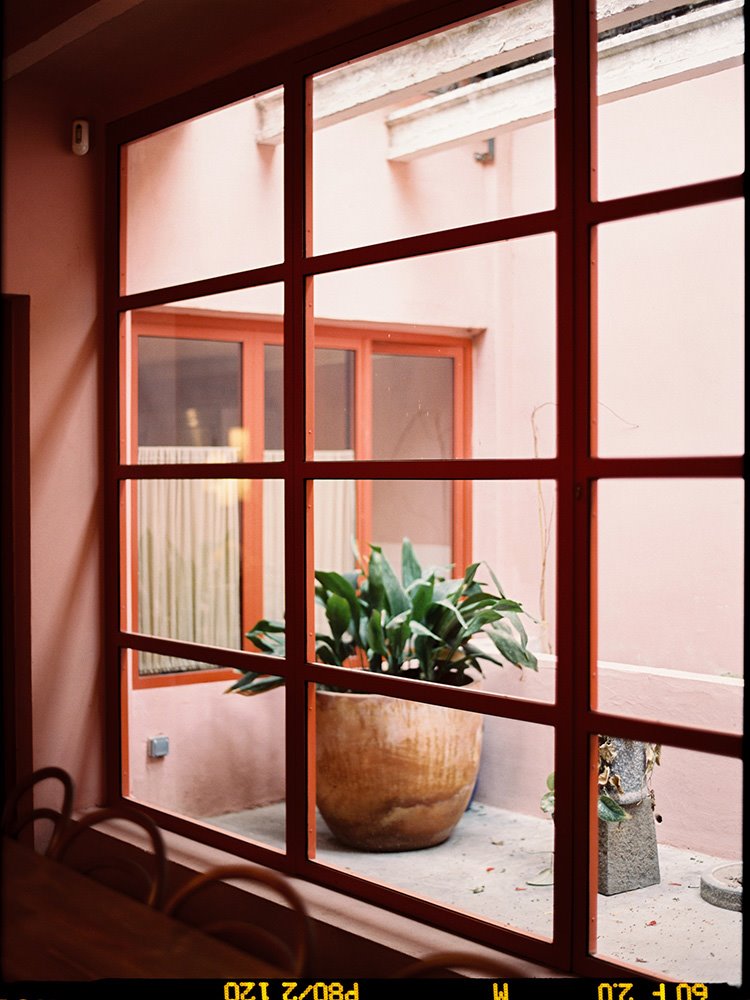 Las puertas acristaladas con carpintería pintada en naranja butano que dan al patio interior de Baldomero. Fotografía de @gemagonzalez_photo 