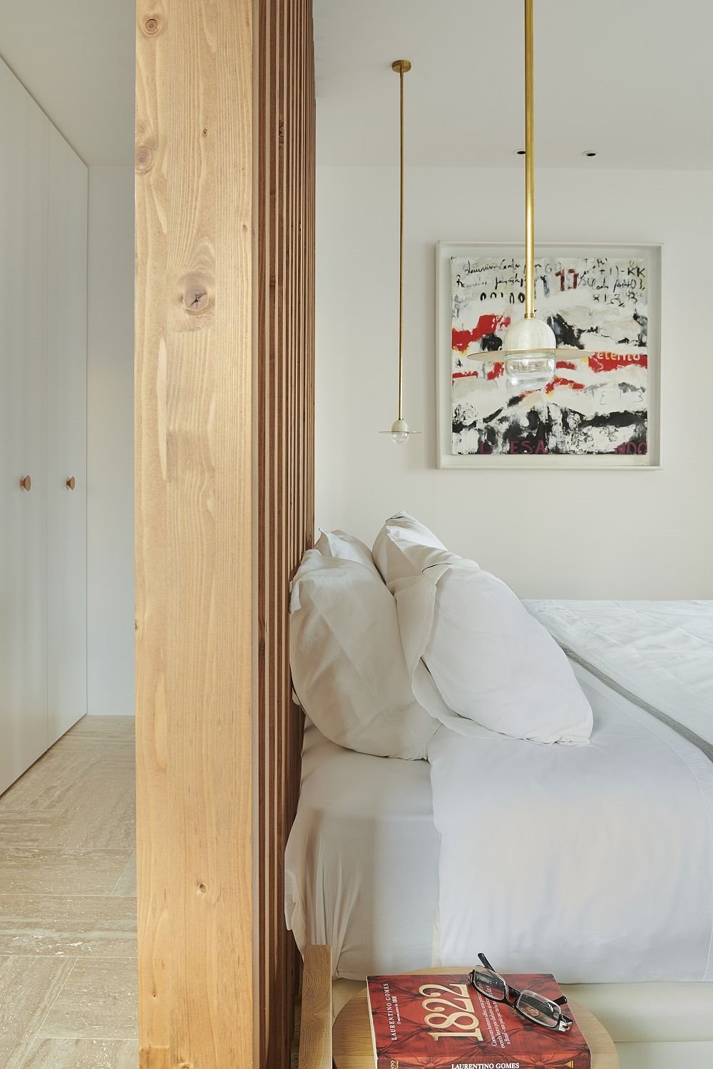 Aunque la cama suele ubicarse pegada a la pared, esta distribución facilita el diseño de un vestidor. La estructura de madera, obra del arquitecto Georg Kayser, hace las veces de cabecero y separador de ambientes.