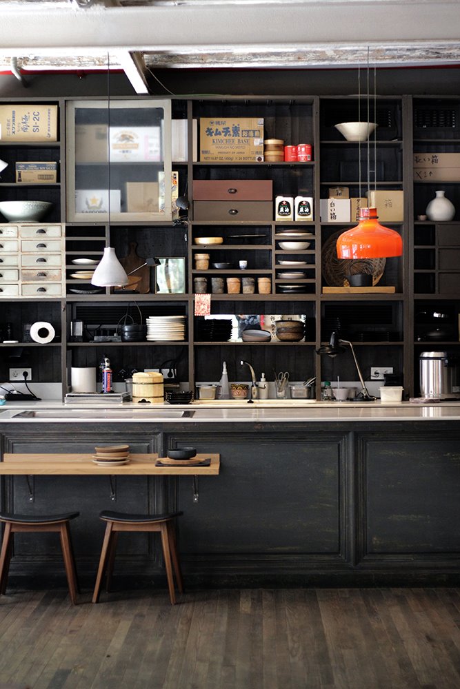 La barra del restaurante, como en una antigua taberna japonesa, está protagonizada por unas enormes estanterías repletas de cajas, cajones, archivadores y cerámicas.