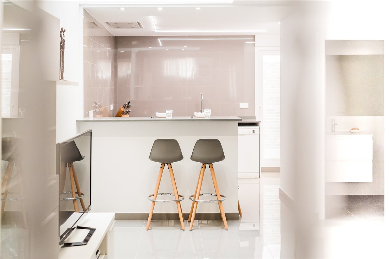 Revestimientos de acabado brillante y cuidada iluminación, los elementos claves de la reforma de esta cocina. (Foto: AMD Estudio)