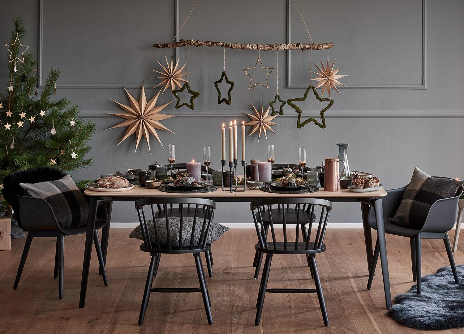 Decoración de una mesa de Navidad con manteles individuales, velas, panes, piñas, vasos tintados, piezas de acabo en cobre y adornos típicos.