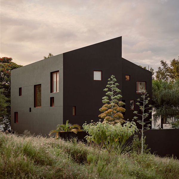 Las ventanas rojas de esta inusual casa con techo asimétrico conectan con el paisaje