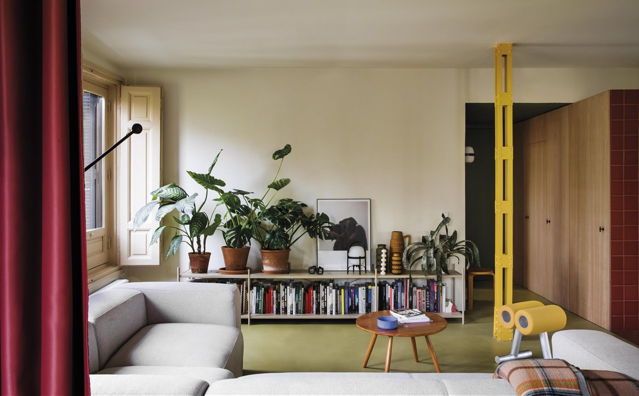 En este espacio, cuyas paredes tienen una base de color beige claro, los pilares metálicos, la cortina de separación y parte del mobiliario consiguen generar un espacio dinámico.