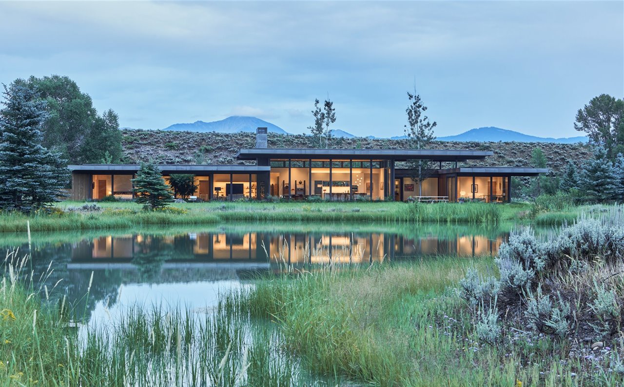La casa ofrece vistas panorámicas a un estanque y las montañas.