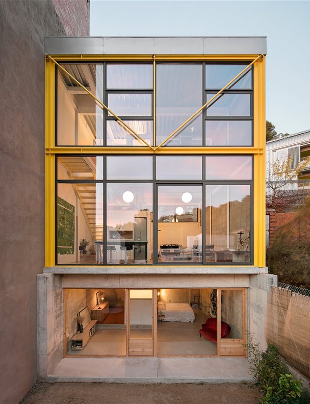 Una casa en amarillo y toques industriales que destaca en el paisaje urbano por su ligereza visual 