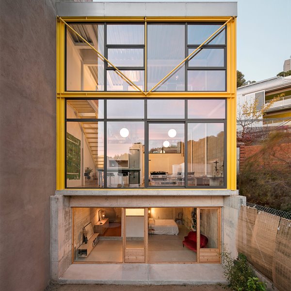 Una casa en amarillo y toques industriales que destaca en el paisaje urbano por su ligereza visual 