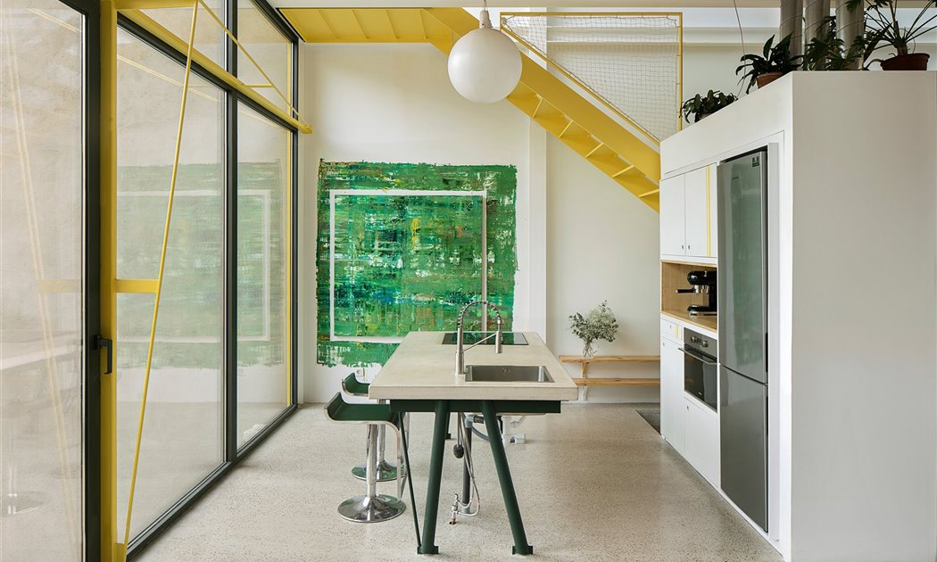 Una casa en amarillo y toques industriales que destaca en el paisaje urbano por su ligereza visual 