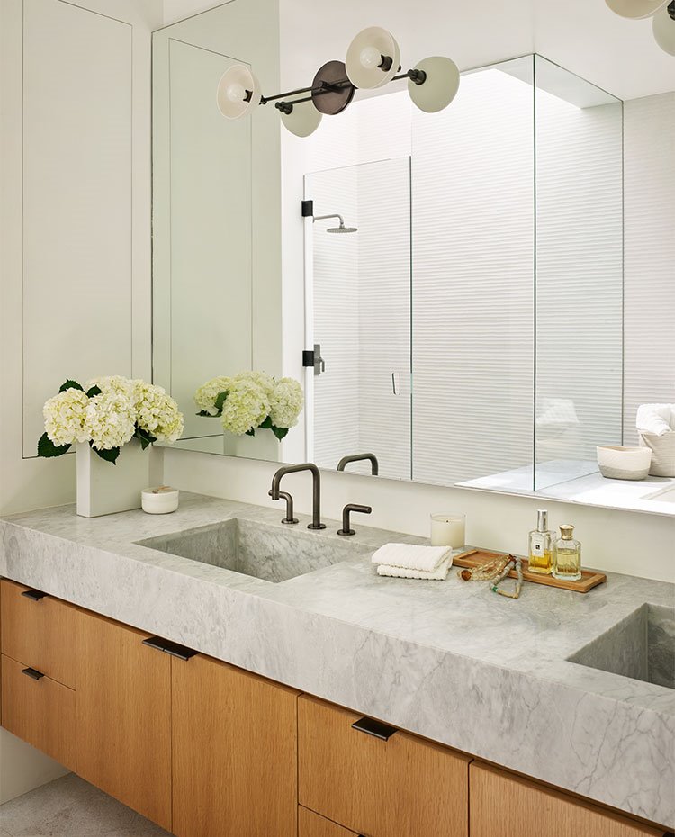 Cuarto-de-baño-con-mueble-suspendido-de-madera-y-amplio-espejo-frontal-en-zona-tocador