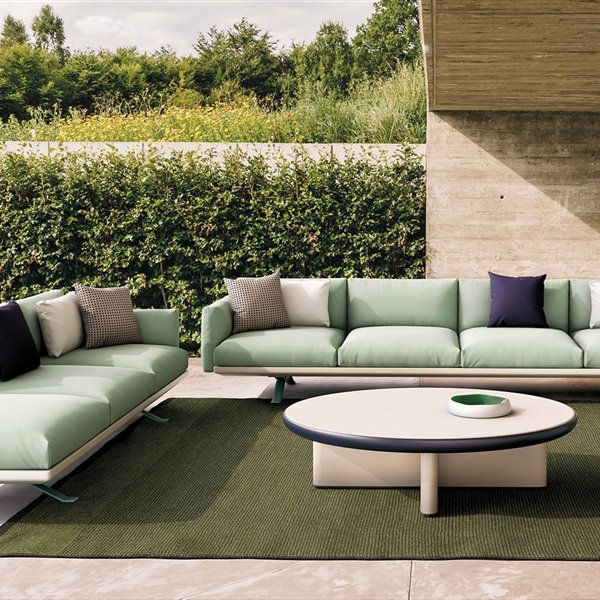 sofa verde de exteriores en un patio de kettal