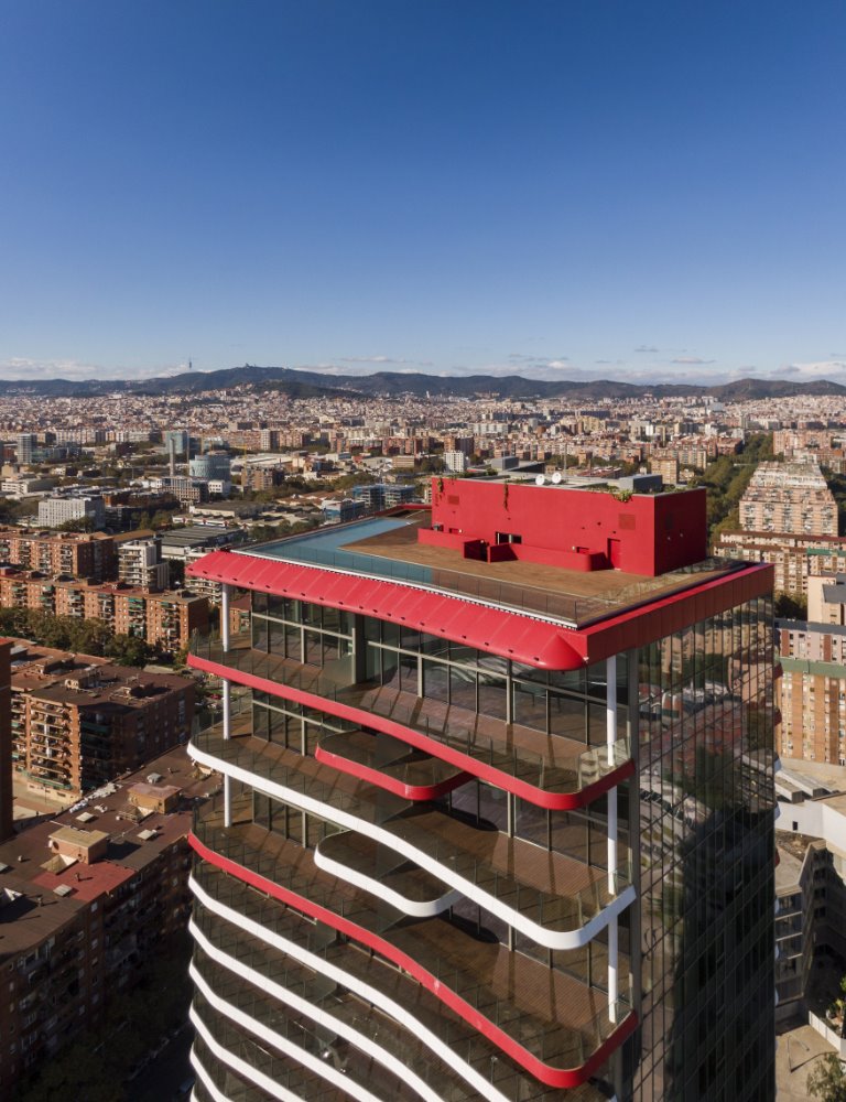 El color rojo aplicado en la cima contribuye a resaltar su presencia y evoca el espíritu vitalista y mediterráneo de Barcelona.