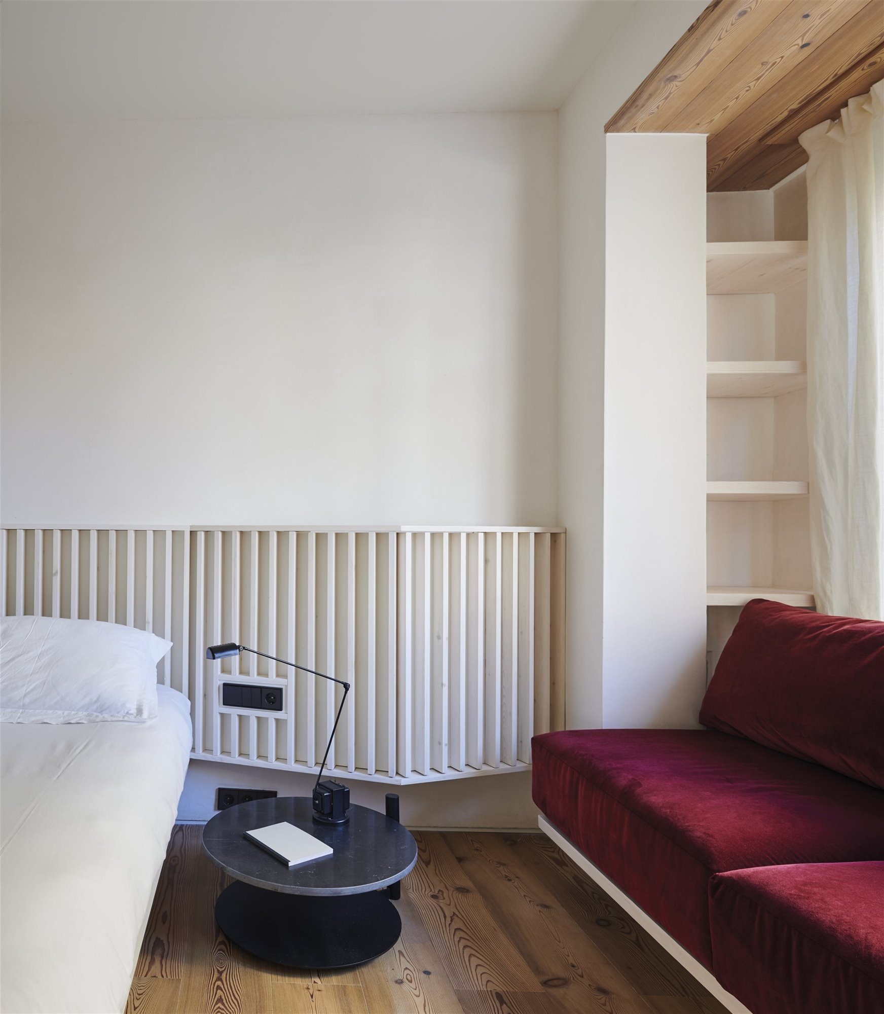 bergnes de las casas dormitorio blanco con sofá terciopelo rojo y mesilla de noche negra