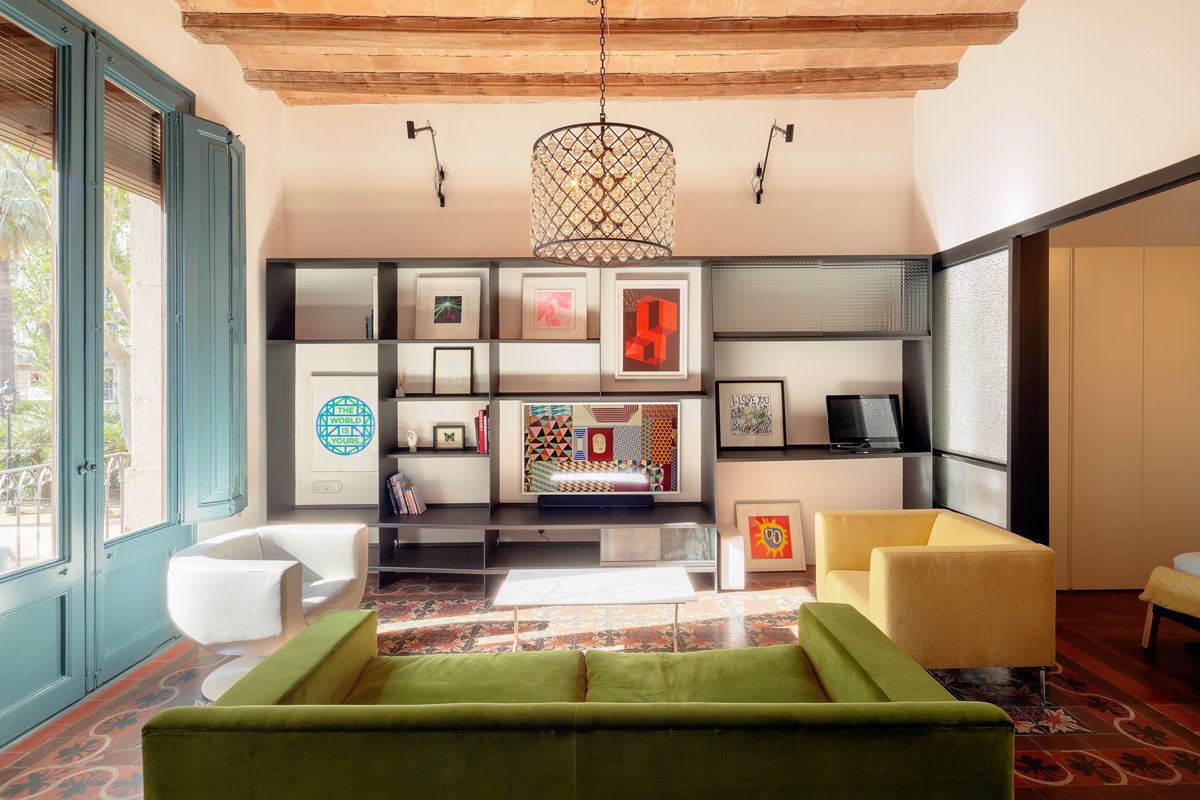 Salón moderno con estantería negra y sofá verde. 