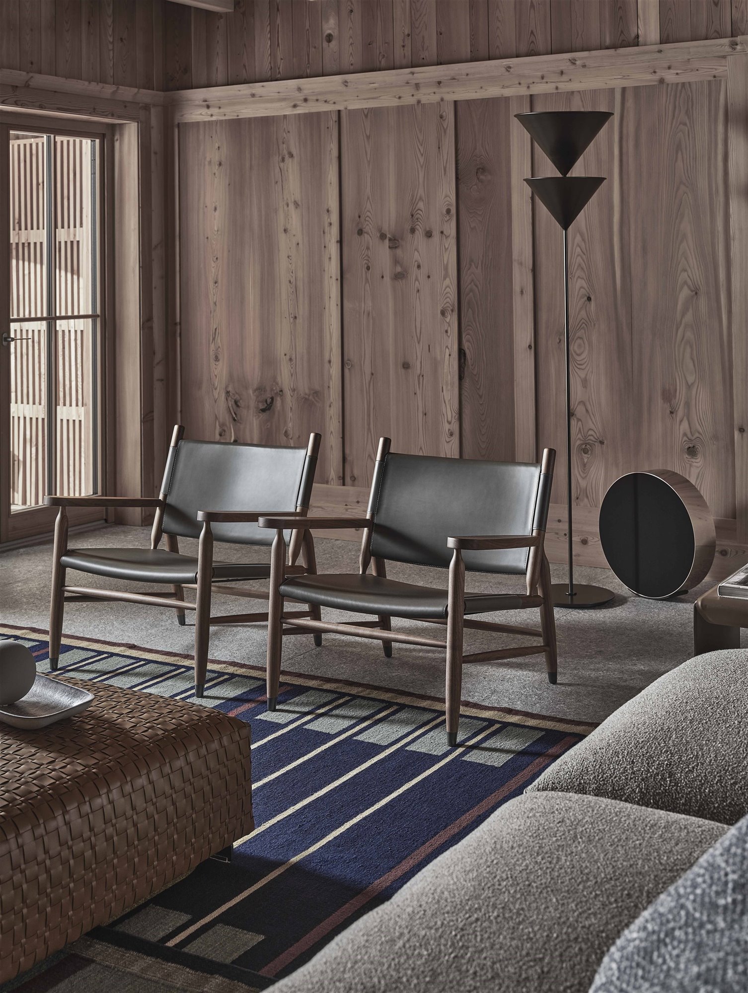 sillón negro de cuero y madera en un salón sobrio con alfombra 