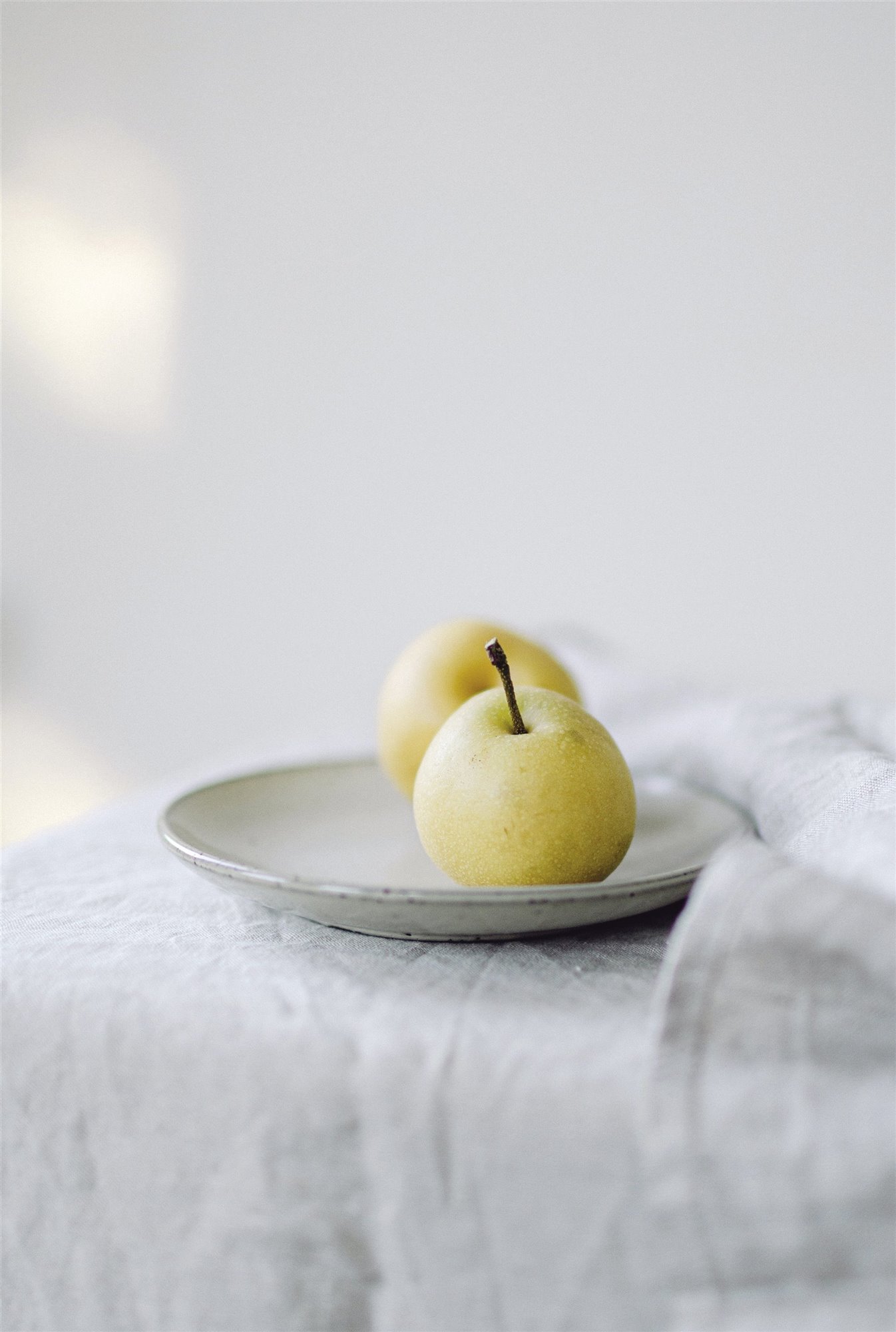 manzanas verde en un plato blanco y mantel