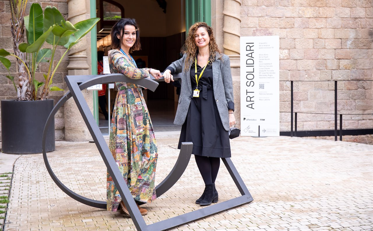 Patricia Cancelo –izquierda– junto a Elisa Llurba, directora de Ginecología y Obstetricia del hospital de Sant Pau, con una de las obras de la artista expuestas en la muestra Art Solidari.