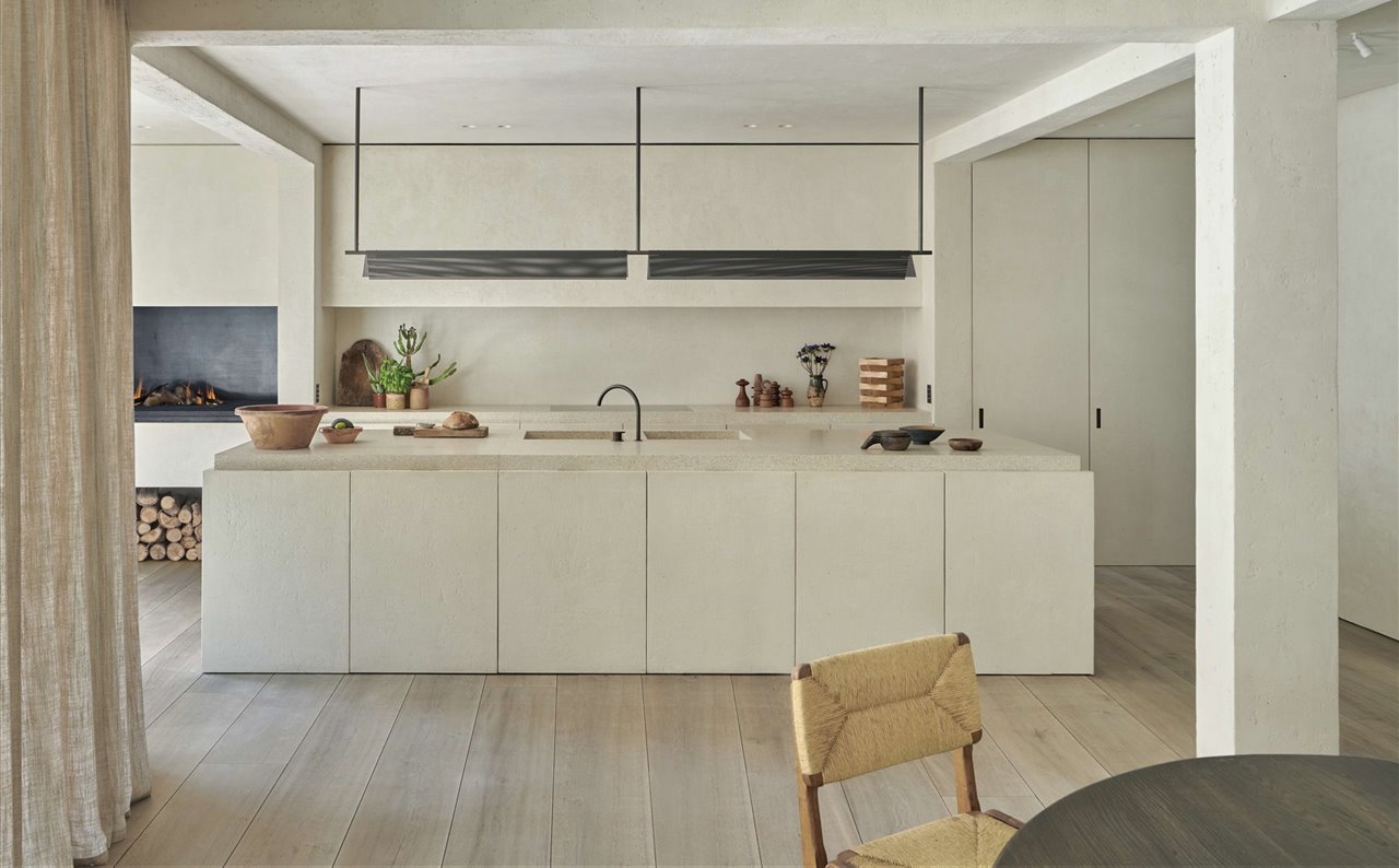 La encimera de la cocina se ha realizado en terrazo, y los grifos, que muestran un acabado de bronce personalizado, son de la firma Vola. La lámpara de suspensión de bronce diseñada a medida por Marc Merckx, al igual que la chimenea de la izquierda.