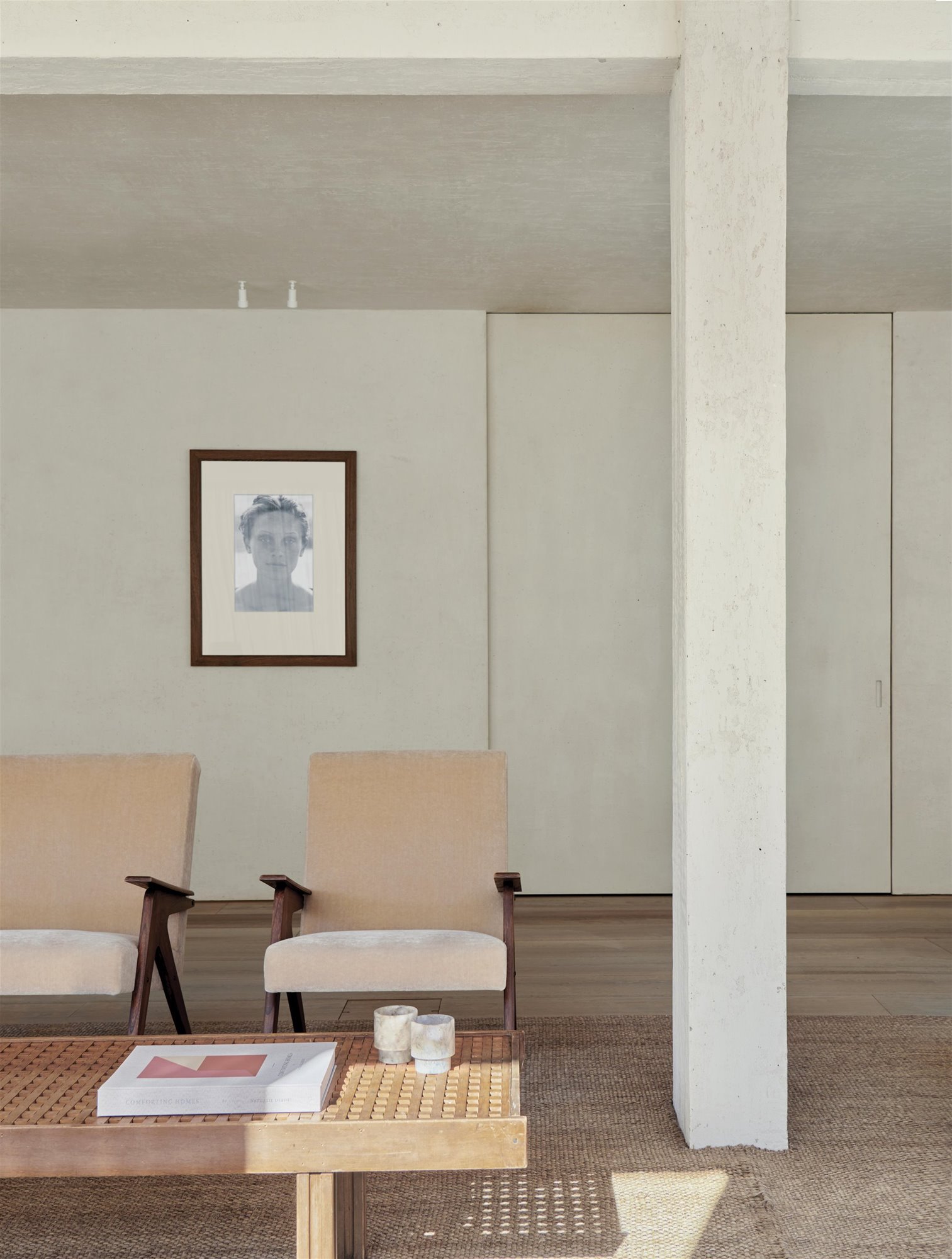 Salón con columna, butacas de terciopelo, mesa de cafe, y fotografia de peter lindbergh.