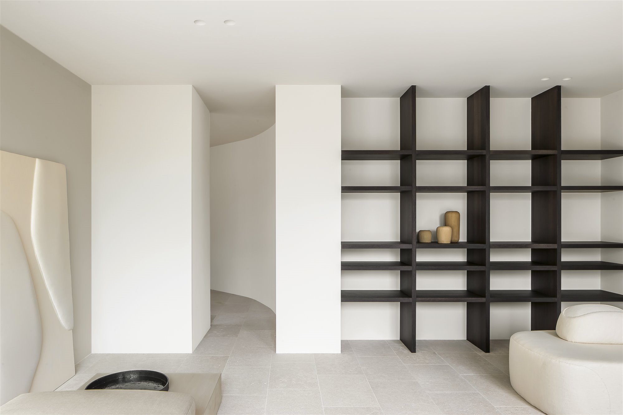 salón minimalista blanco con estantería oscura y cuencos