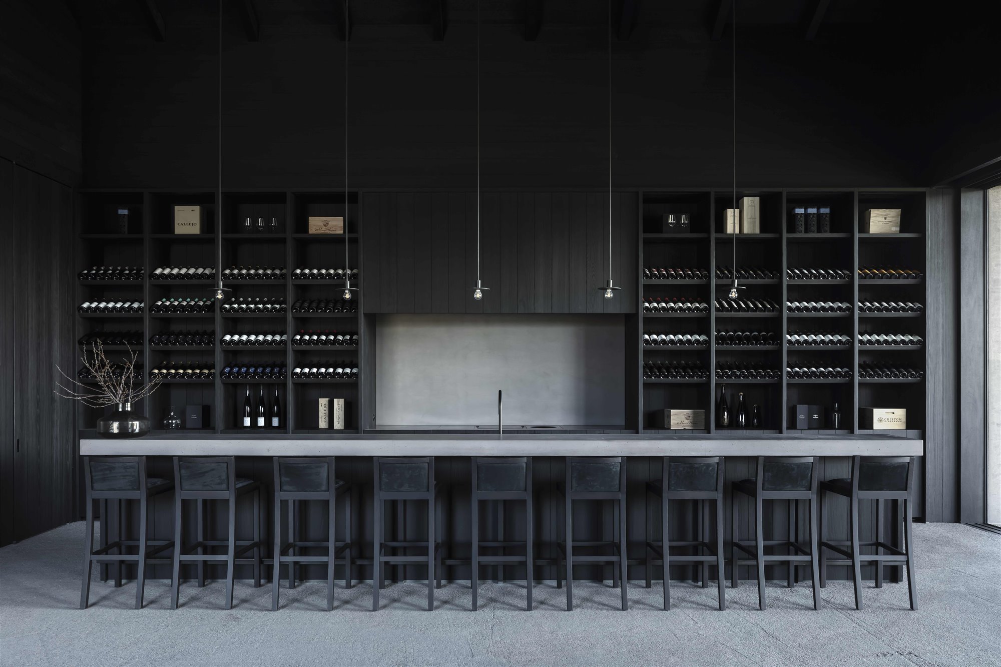 mesa con taburetes y botellas de vino bodega Valke Vleug de Vincent Van Duysen