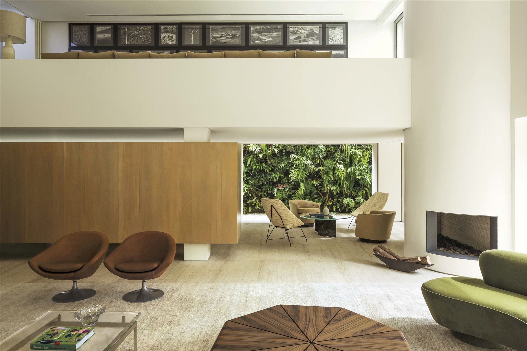 salón moderno con butacas marrones, chimenea en columna y mesa de cristal de arthur casas