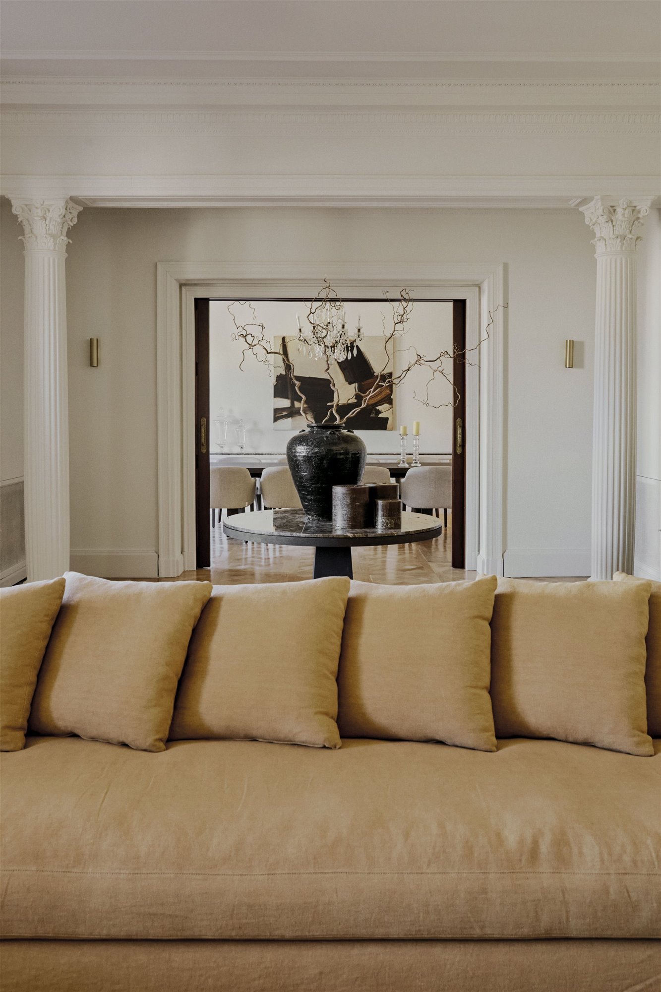salón con columnas sofá beige y jarrón negro con flores secas