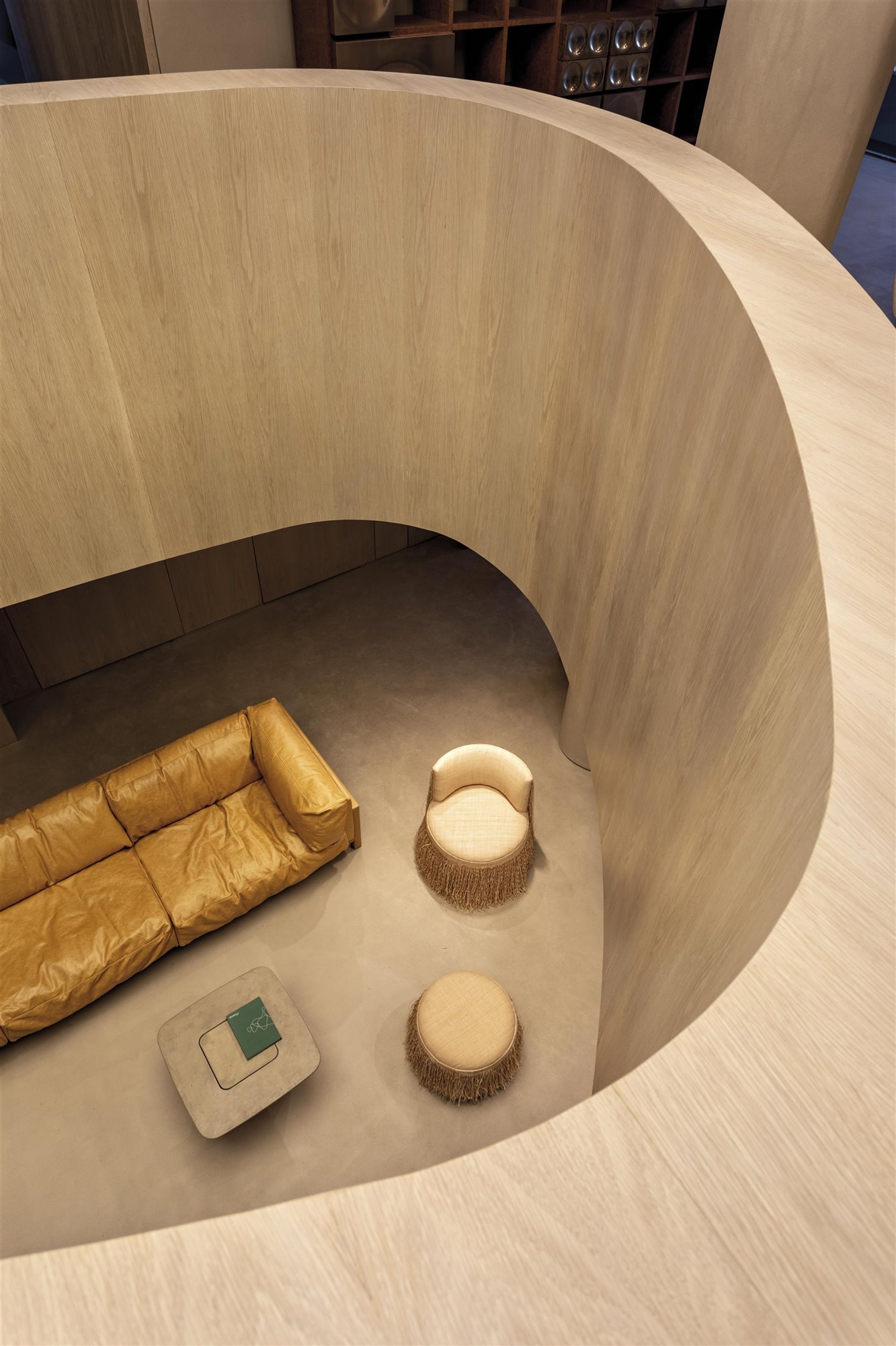 salón de madera visto desde arriba con sofá de piel y butaca con reposapiés beige de arthur casas