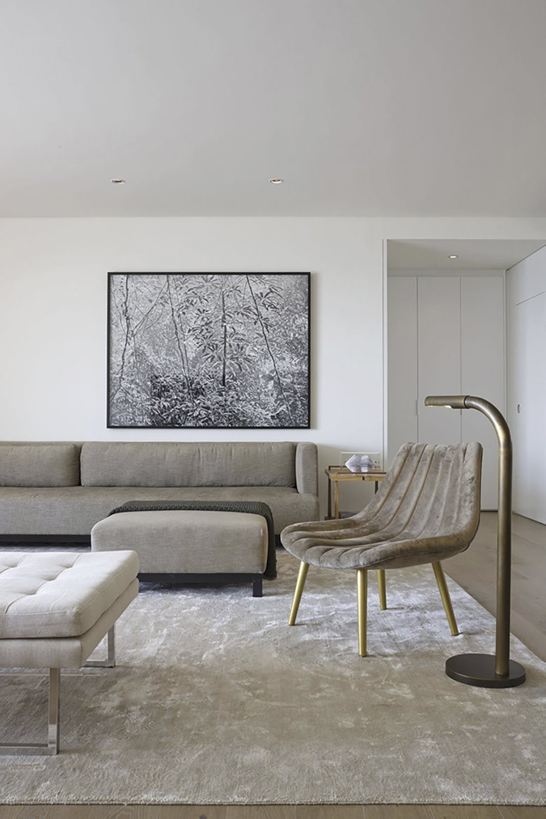 salón gris con sofá butaca cuadro y lámpara de pie dorada de arthut casas