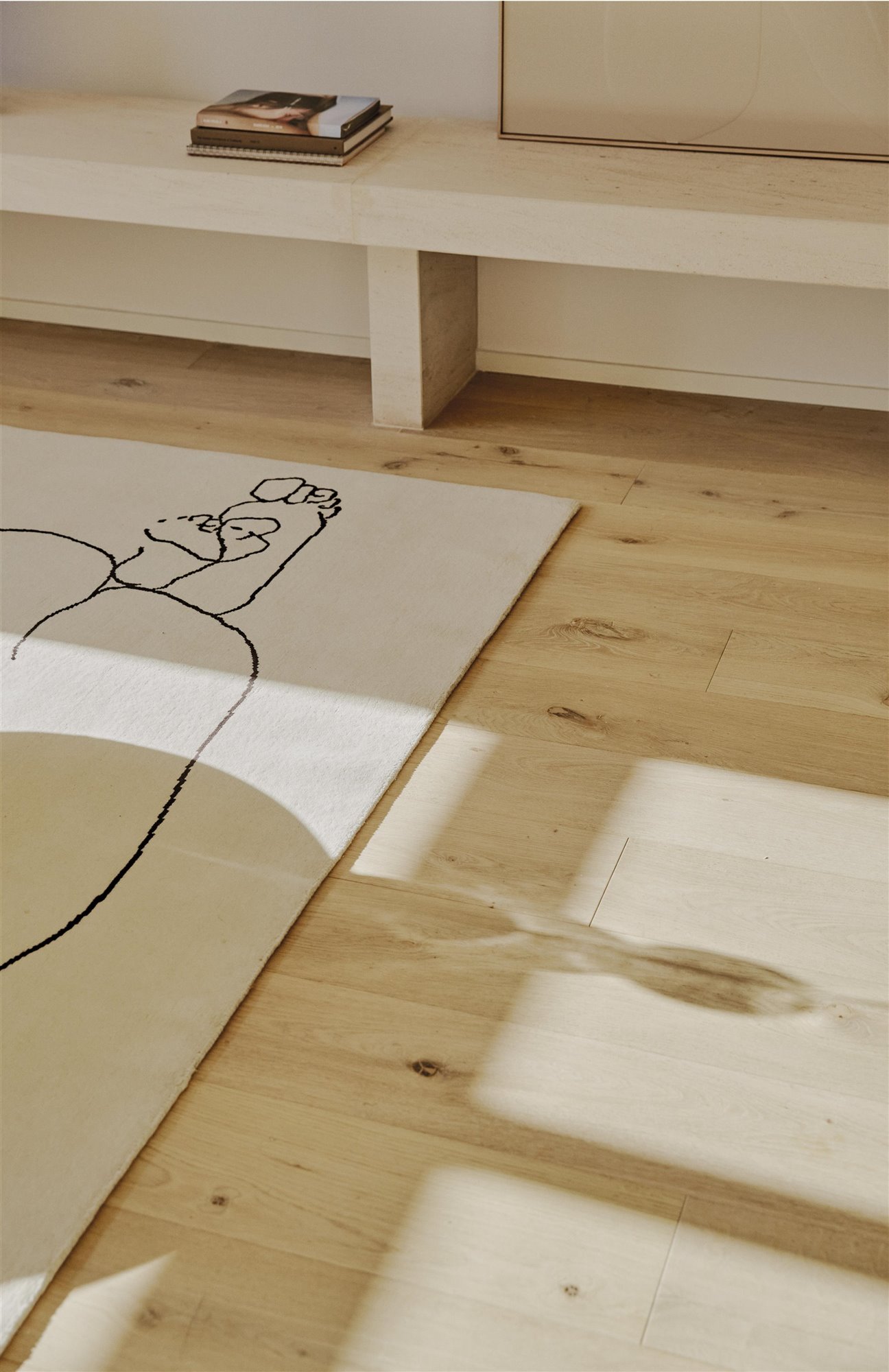 alfombra blanca con pies y banco de madera con libros