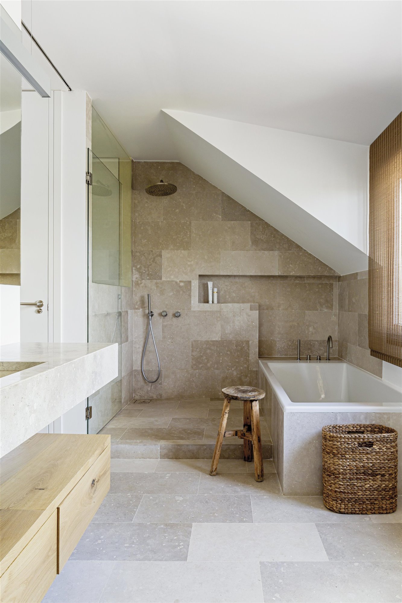 baño de piedra con bañera, cesto de mimbre y taburete de madera
