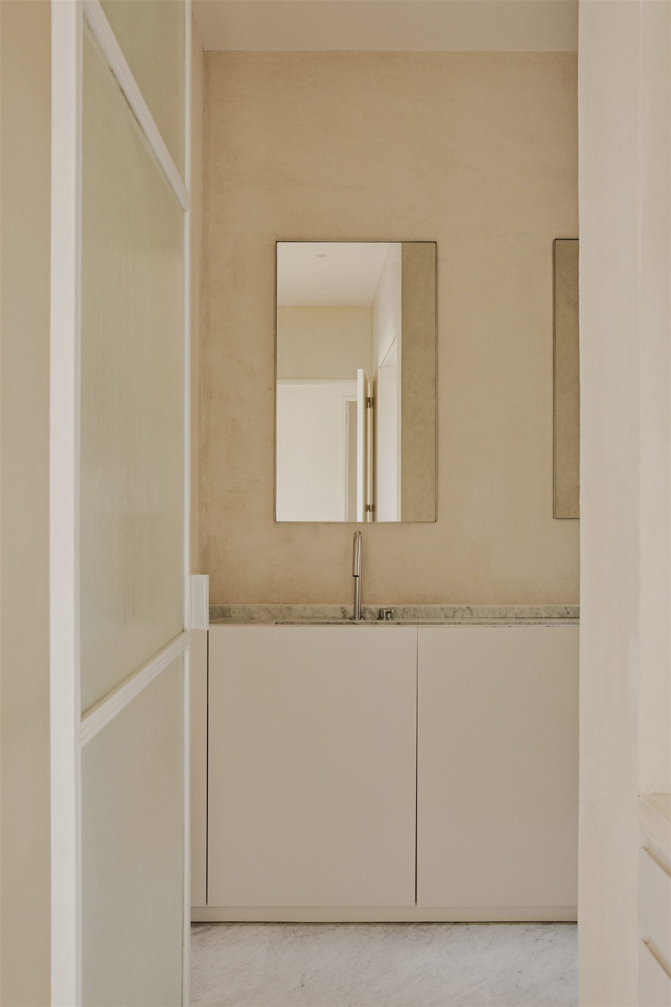 baño minimalista blanco con grifo plateado