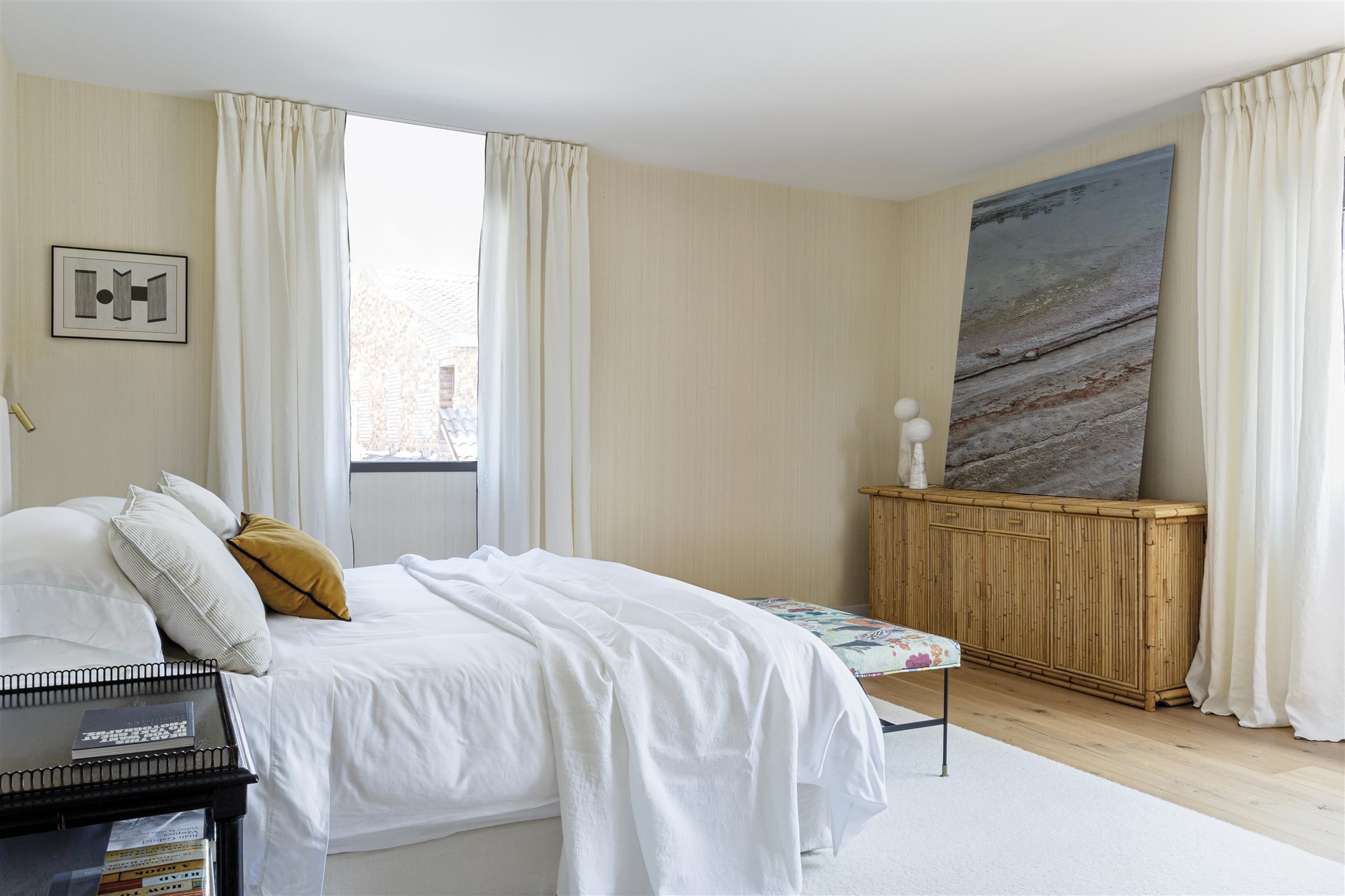 dormitorio con cama de sábanas blancas, mueble de madera y cuadro