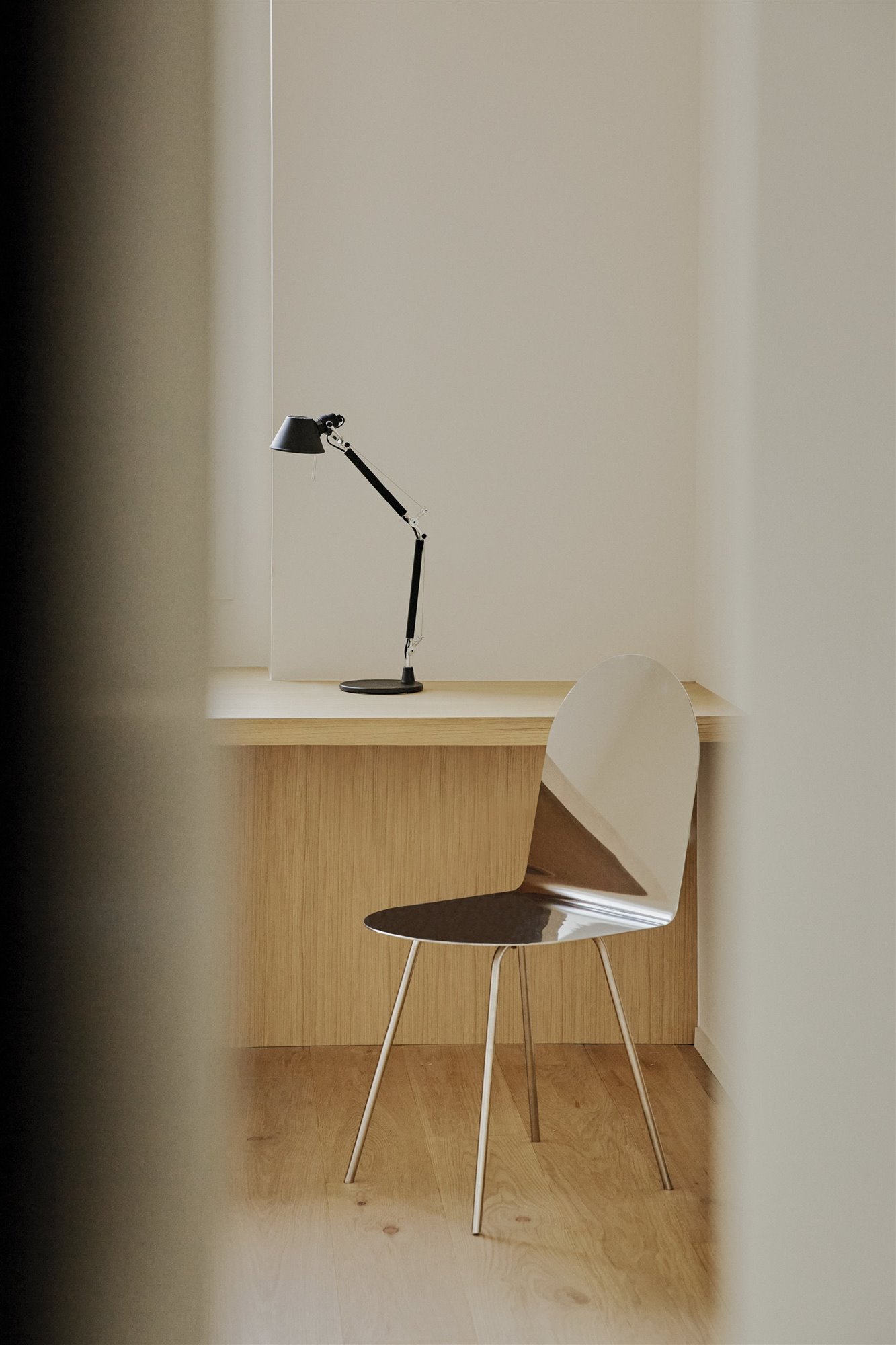 escritorio de madera con flexo negro y silla metálica