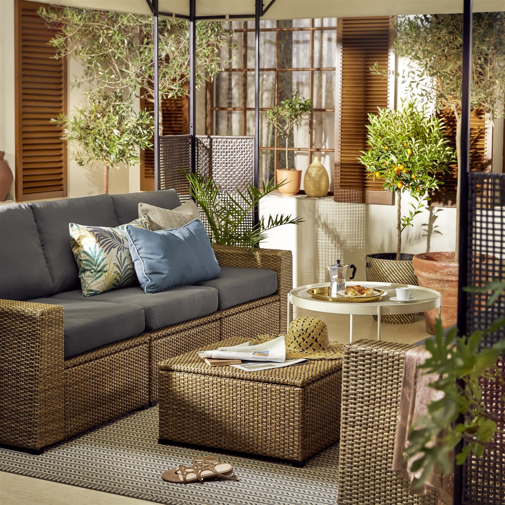 sillón de exterior trenzado con cojines en un patio con plantas 