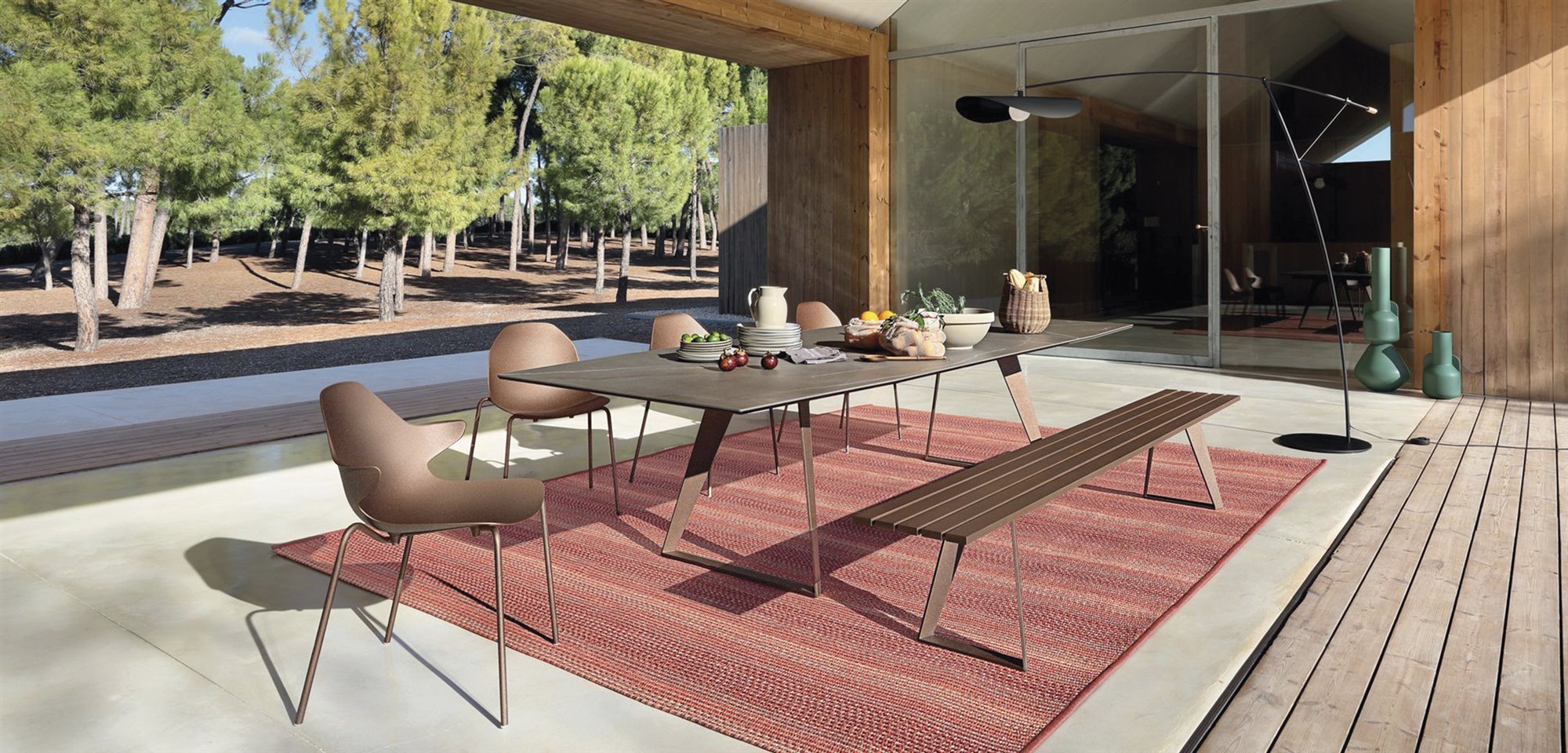 terraza con piscina con mesa de comedor rectangular con banco y sillas y alfombra roja