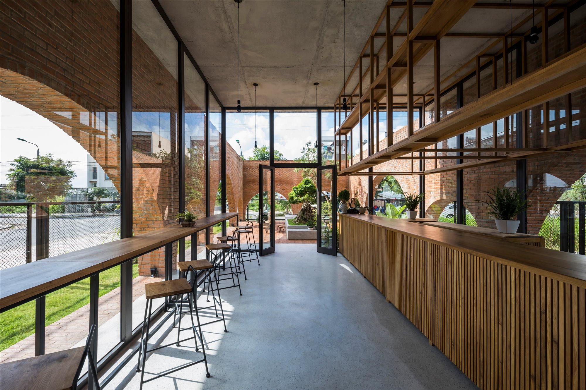 cafetería en casa de ladrillos con cristalera al patio y taburetes
