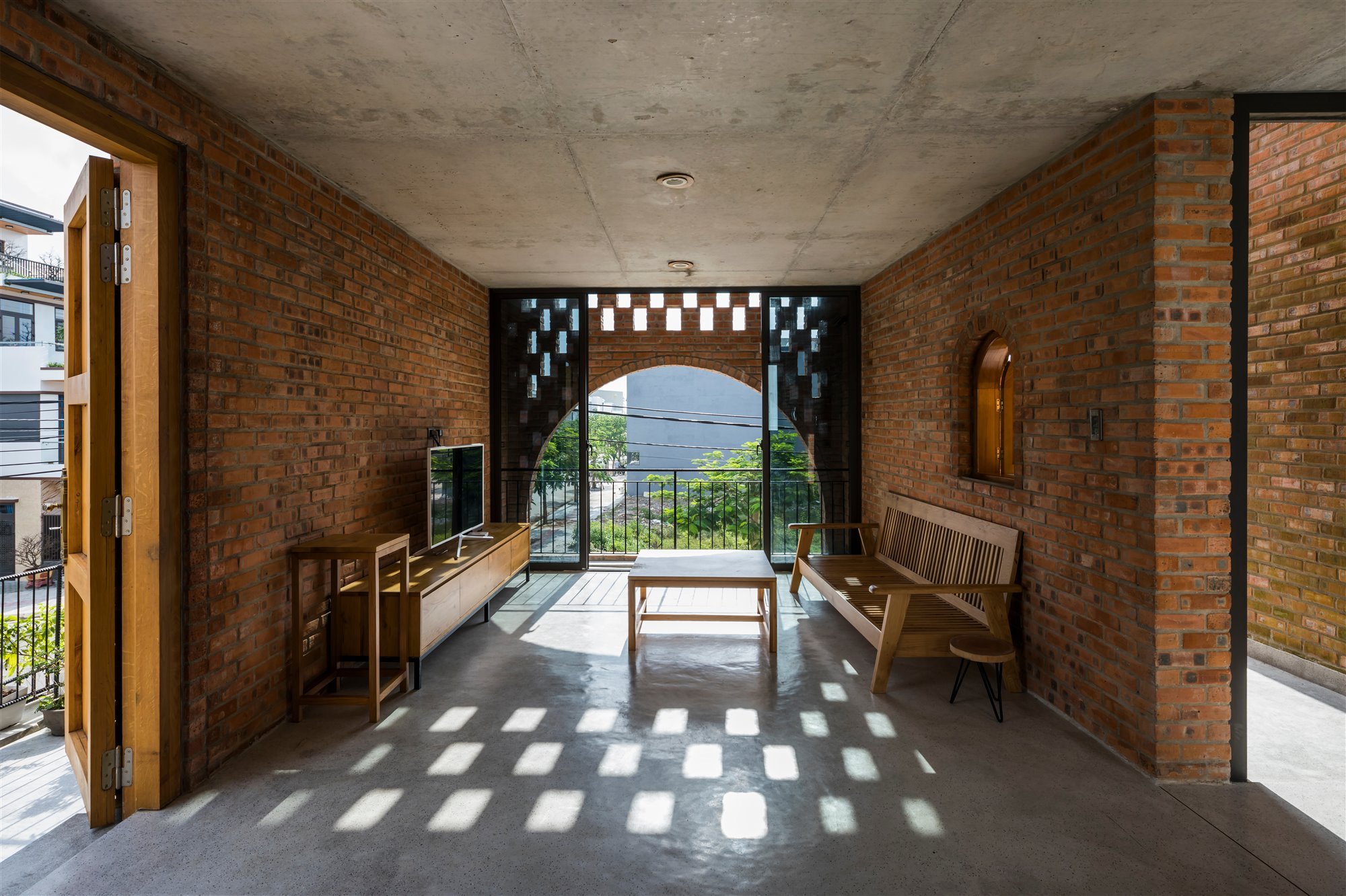 salón casa de ladrillos con celosía banco de madera y televisión