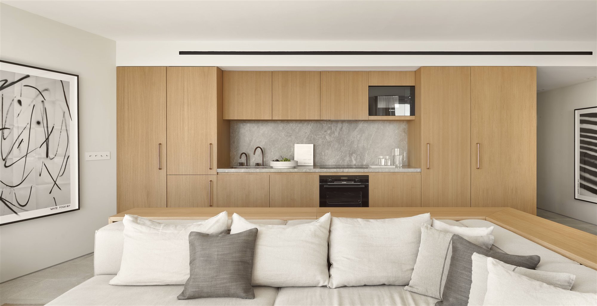cocina americana abierta al salón de madera clara y paredes gris