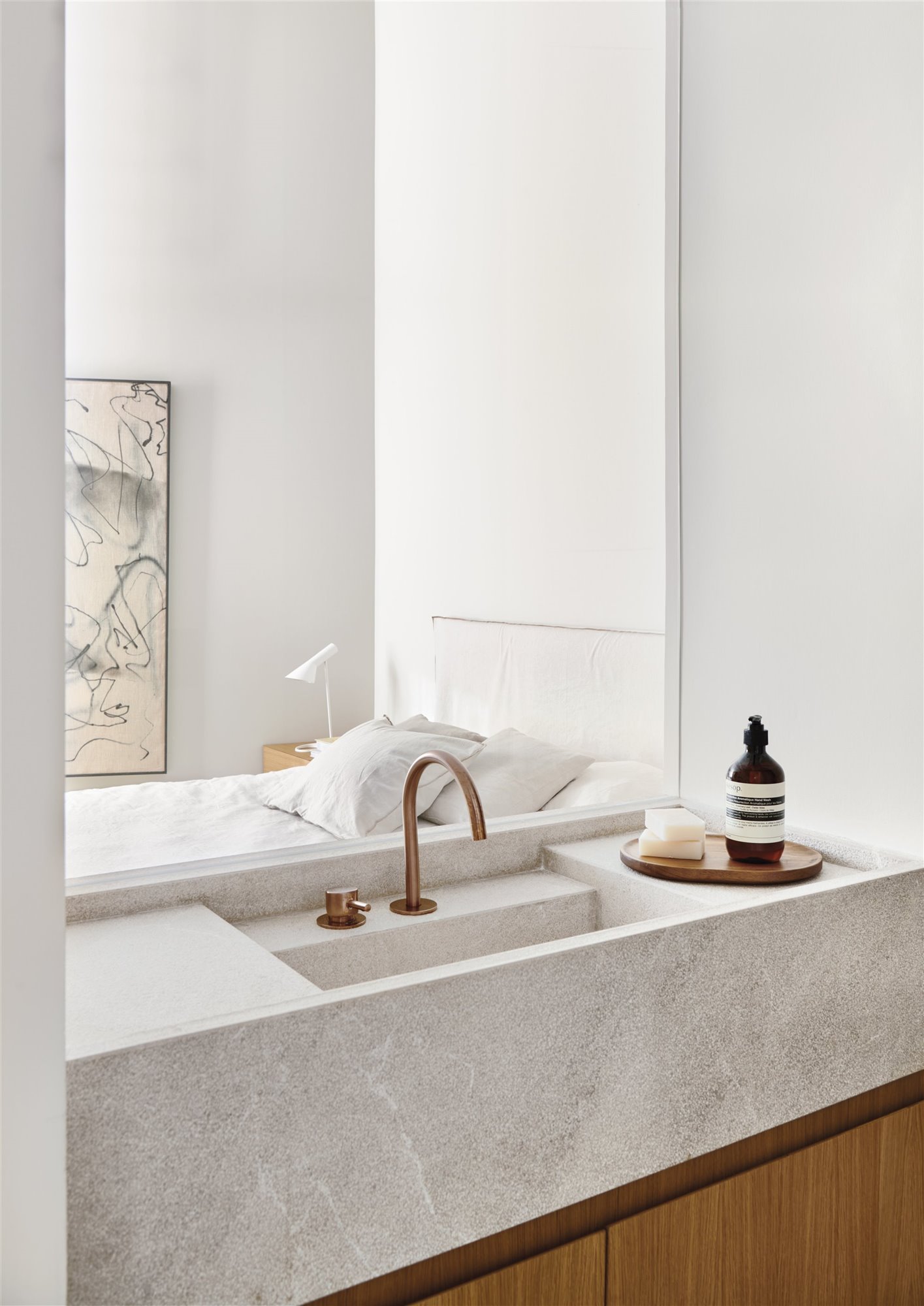 lavamanos de baño en mármol con grifo de bronce y armario de madera, bandeja con productos